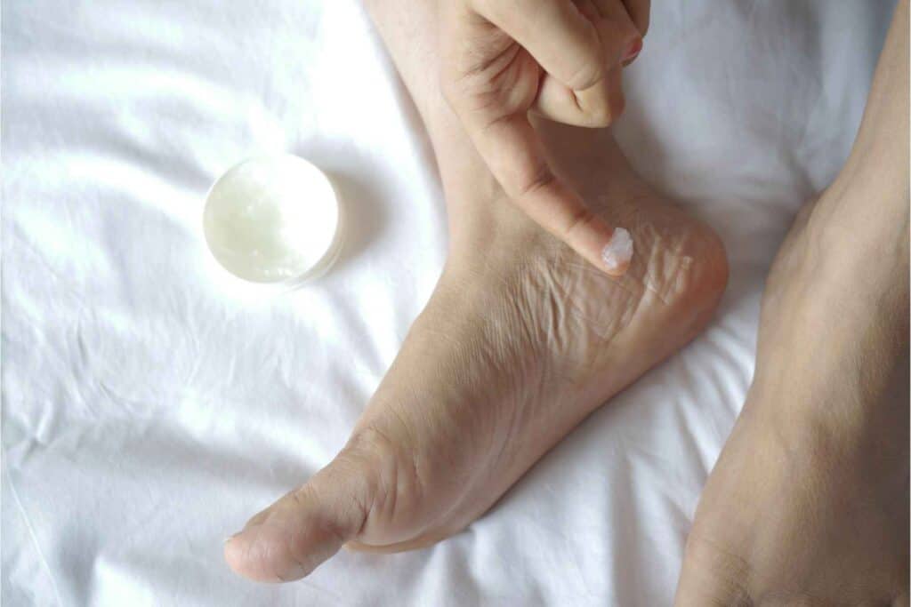 A person applying cream on feet