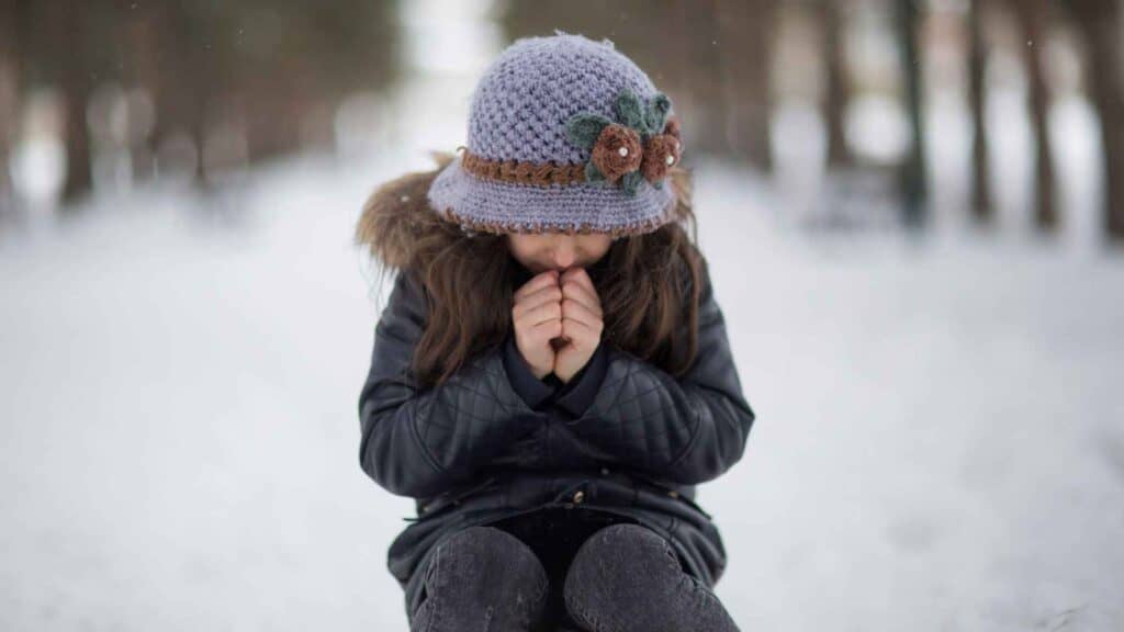 A kid sitting in cold weather