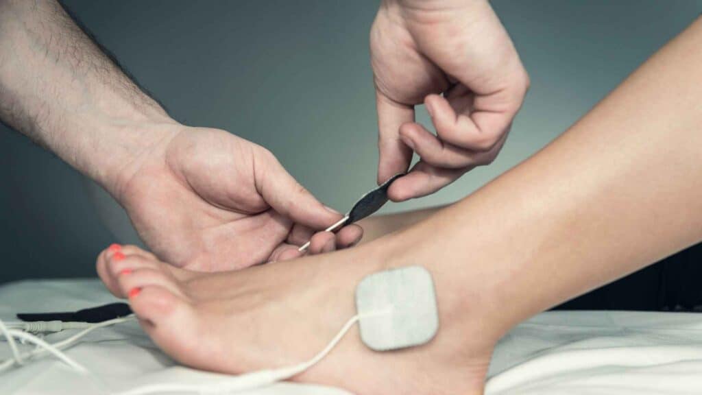 A man putting TENS electrodes on foot