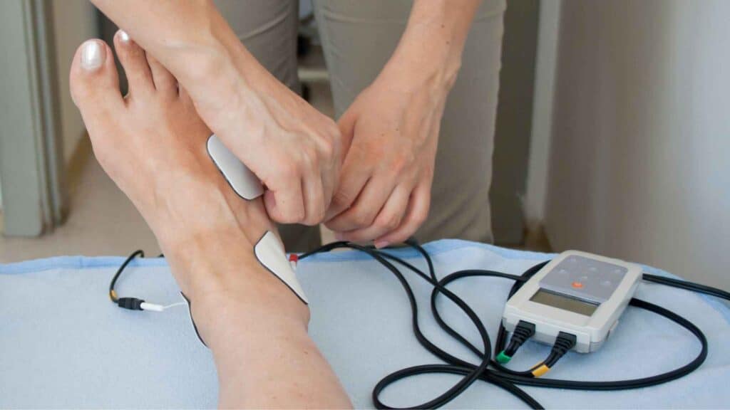 A man adjusting TEN DEVICE electrodes on foot