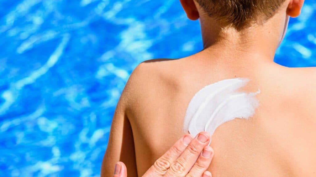 A boy being rubbed by sunscreen on back