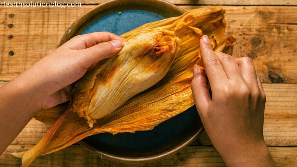 A man opening tamales from its cover